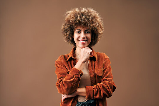 Smiling woman with curly hair in orange corduroy shirt.