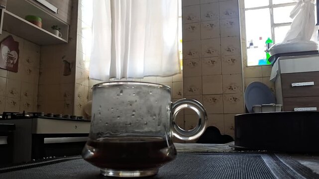 Glass mug of hot coffee resting on kitchen table surface