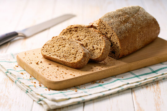 loaf of freshly whole grain yeast-free buckwheat bread with flax seeds on white kitchen table.