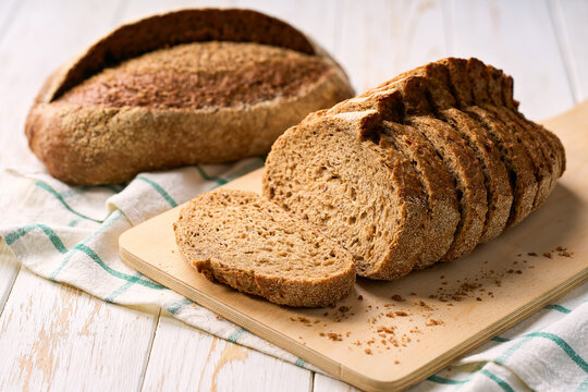 loaf of freshly whole grain yeast-free buckwheat bread with flax seeds on white kitchen table.