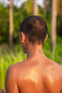 Sweaty Back of A Man With a Tattoo Stands in a Lush Outdoor Setting