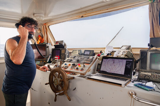 Fisherman using radio in commercial fishing boat wheelhouse