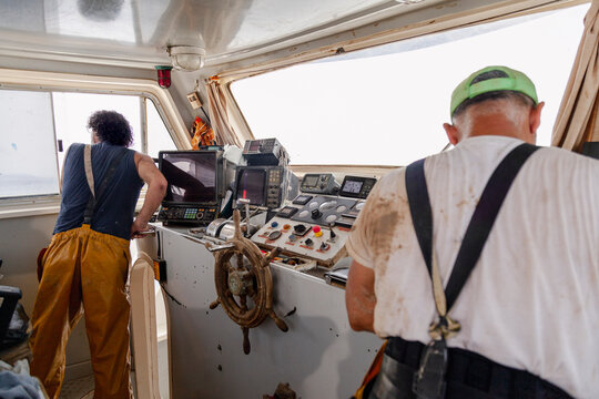 Anonymous fishermen working inside the wheelhouse of a fishing boat