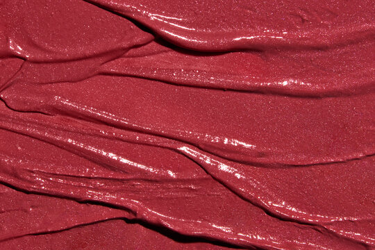 Bright red lipstick texture smeared with waves and imperfections