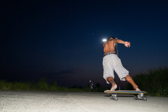 Skater Riding at Night on a Quiet Road Under Street Lights