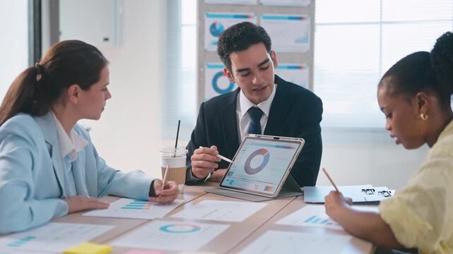 Diverse business team presenting data charts on a tablet and data document during a meeting