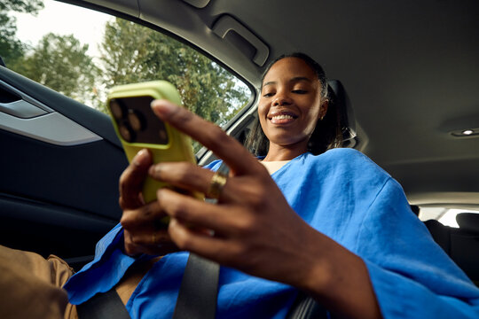 Woman smiles while using her mobile phone in a car