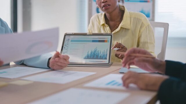 Business team presenting data charts on a tablet and data document during a meeting