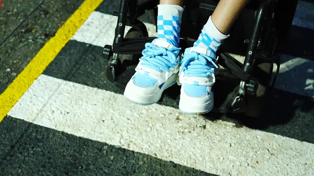 Wheelchair user navigating a city street on a pedestrian zebra crosswalk