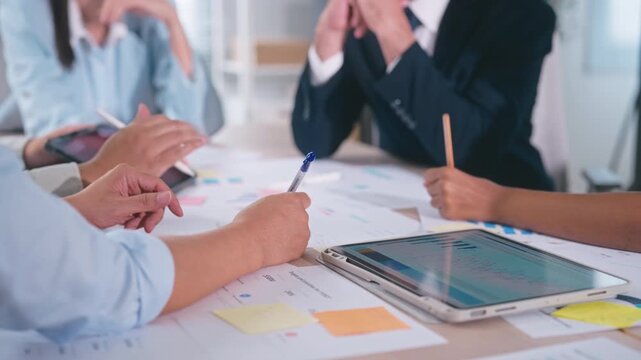 Business team takes notes, reviews documents, and analyzes financial data meeting in office.