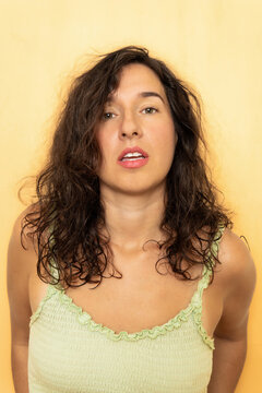 Young woman with curly hair on yellow background