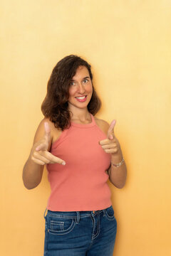 Young woman smiling and pointing finger guns with confidence