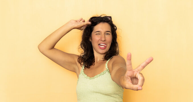 Playful woman winking sticking tongue out showing peace sign