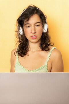 Woman wearing headphones working on laptop with focus