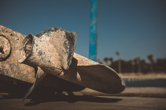 Close up view of damaged and corroded boat propeller covered in sand