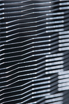 Vertical macro photograph showing silver metal radiator fins in abstract wavy linear pattern.