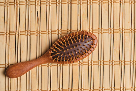 Flat lay top view an eco friendly wooden hairbrush resting on bamboo mat background.