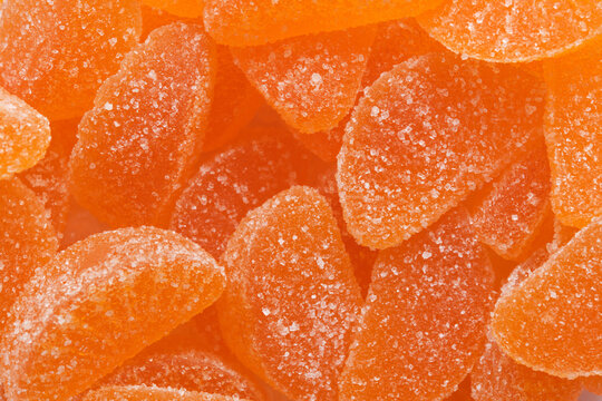 Macro texture background orange citrus slice marmalade candies coated with sparkling sugar crystals.