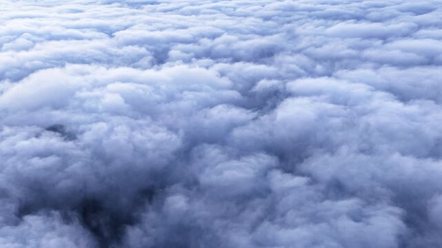 High angle shot reveals a vast sea of fluffy white and blue clouds stretched across the sky, creating a peaceful scene.