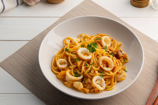 Stir fried linguine pasta with squid and chilli ,garlic with olive oil in white plate.Octopus Spaghetti Aglio e Olio.