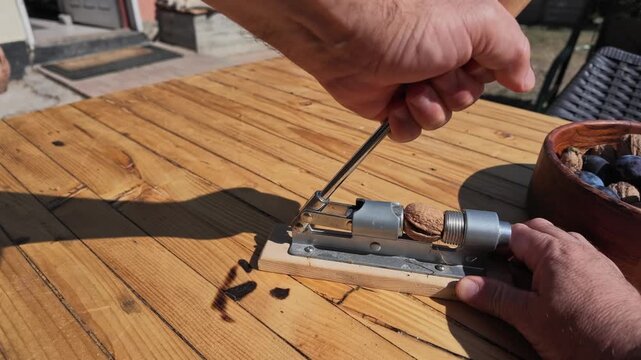 Slow Motion POV of Man Cracking Walnuts at the Table Outdoors