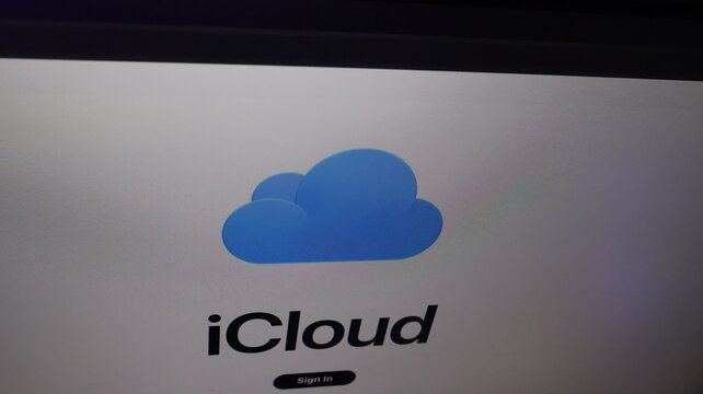 Apple icloud logo with blue cloud symbol and bold black text on white background login screen interface with sign in button visible at the bottom of the display.