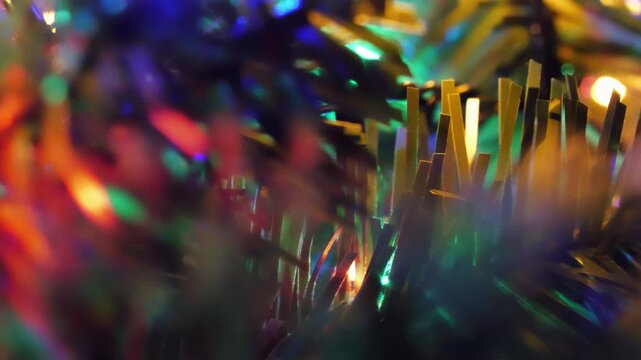 Closeup macro of colorful blinking Christmas tree lights glowing and twinkling on pine branches with soft bokeh background