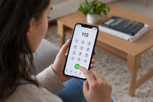 a person with the digits 112 visible on their mobile phone screen