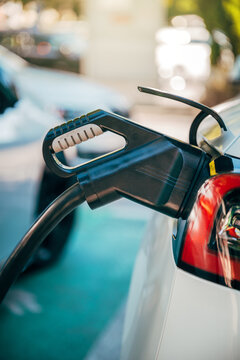 Electric car connected to a charging station with EV charging cable and connector in closeup. Renewable energy, zero emissions, sustainable transportation and green technology theme.