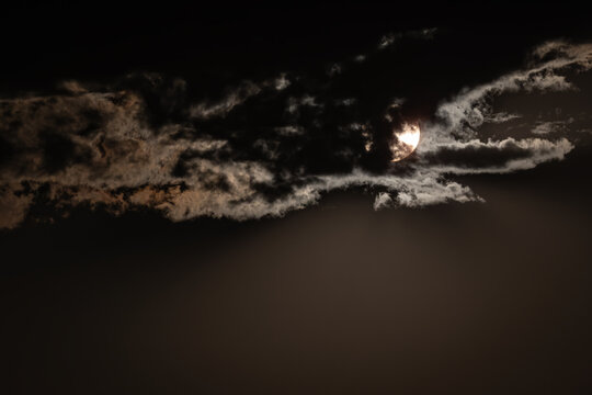Sun peeking through clouds photographed with an ND filter.