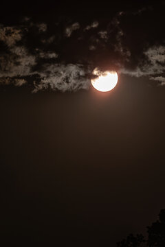 Sun peeking through clouds photographed with an ND filter.