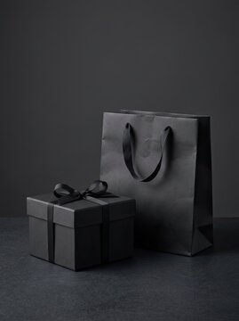 Elegant black gift box and shopping bag on a dark moody background