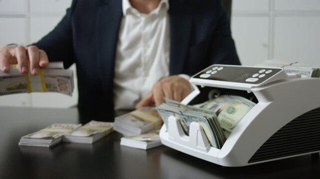 Banker counting cash in office. Banker managing finance. Banker controlling money and verifying dollars. Banking financial process. Office scene with banker and counting machine.
