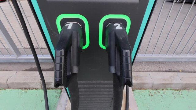 Electric vehicle charging station with two plugged connectors with green LED light