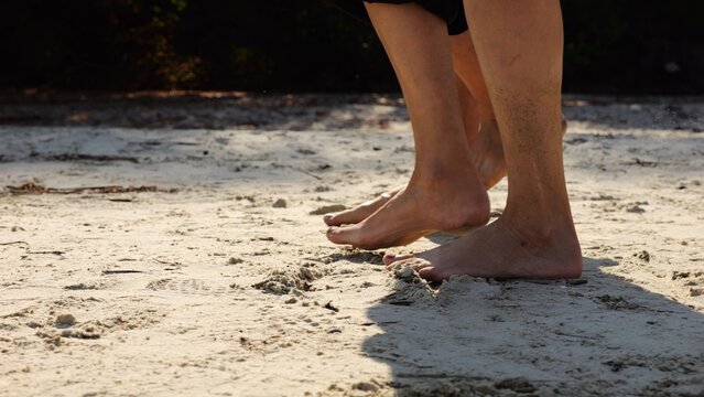 Male and female legs of pair walking on sandy beach. Bare feet of couple stepping along sand shore at sunny day. Lovers spending time together at resort. Concept of summer vacation or holiday