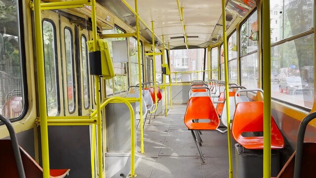 Empty tram moves along city street at sunny summer day. The calm street and passing tram capture urban life and modern public transportation in motion, emphasizing rhythm, movement and city flow
