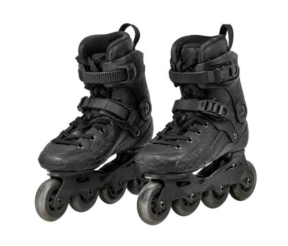 Pair of black aggressive inline skates with four wheels each, showing signs of wear and tear, isolated on a clean white background