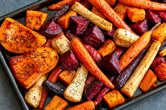 Roasted root vegetables with butternut squash, carrots, beets and parsnips seasoned with herbs on baking tray