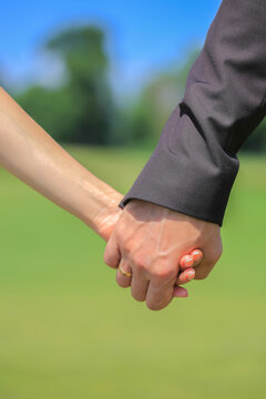 Close up view of a romantic couple walking and holding hands in a park