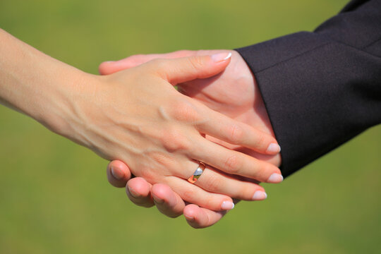 Close up of a newlywed couple holding hands showing wedding ring