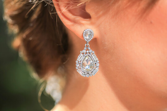 Detailed macro view of an elegant crystal drop earring worn by a woman with brunette hair