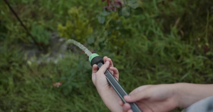 Close-up children hands watering plants in backyard. 4K 10-bit