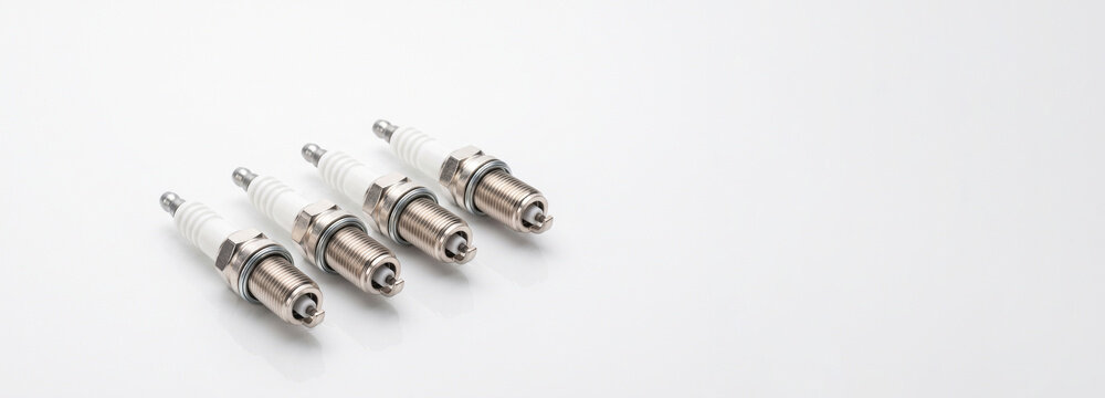 Four car spark plugs arranged in a row with copy space for text