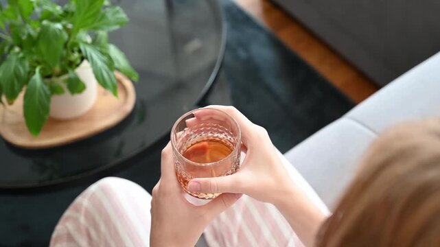 Person Relaxing on Sofa with Refreshing Drink at Home