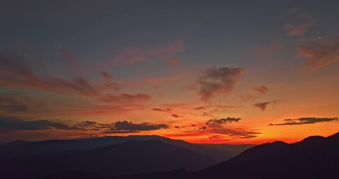 aerial panoramic image features a mountain range at sunset. Vibrant pink and golden skies illuminate the rugged peaks. Ideal for travel,or landscape projects, it works well as a background or banner