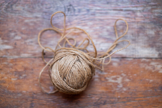 Ball of natural jute twine with loose loops on old weathered wooden boards, rustic craft string and eco packaging material, top view