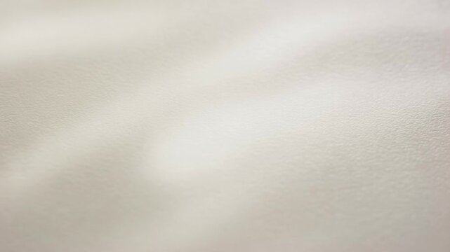 Soft neutral wall texture with diffuse light shifting across a pale indoor surface. Text overlay, interior design mood board, and minimalist advertising.