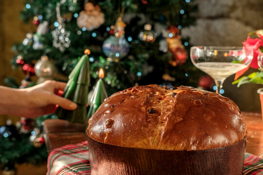 Christmas panettone with candle and champagne beside a decorated tree