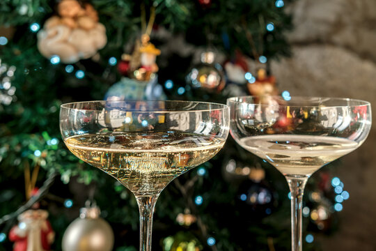 Champagne glasses with sparkling wine beside a decorated Christmas tree