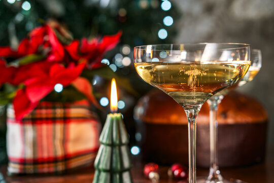Christmas celebration with champagne coupe glasses, sparkling wine and candle beside a poinsettia